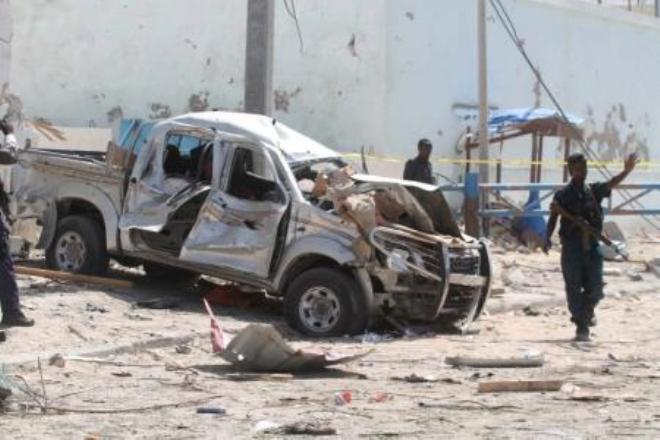A policeman gives instructions near the wreckage of a car destroyed during a suicide bombing near the African Union"s main peacekeeping base in Mogadishu, Somalia, July 26, 2016.